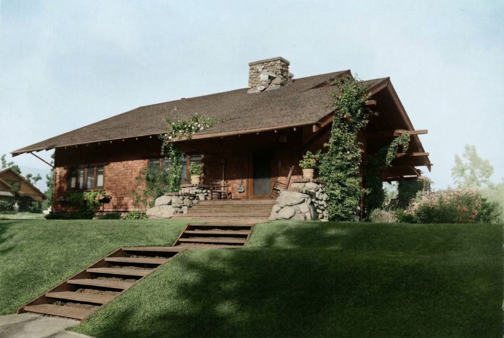 Historic colorized exterior of Louise Halsted house with stone chimney, wood shingles, and terraced lawn steps