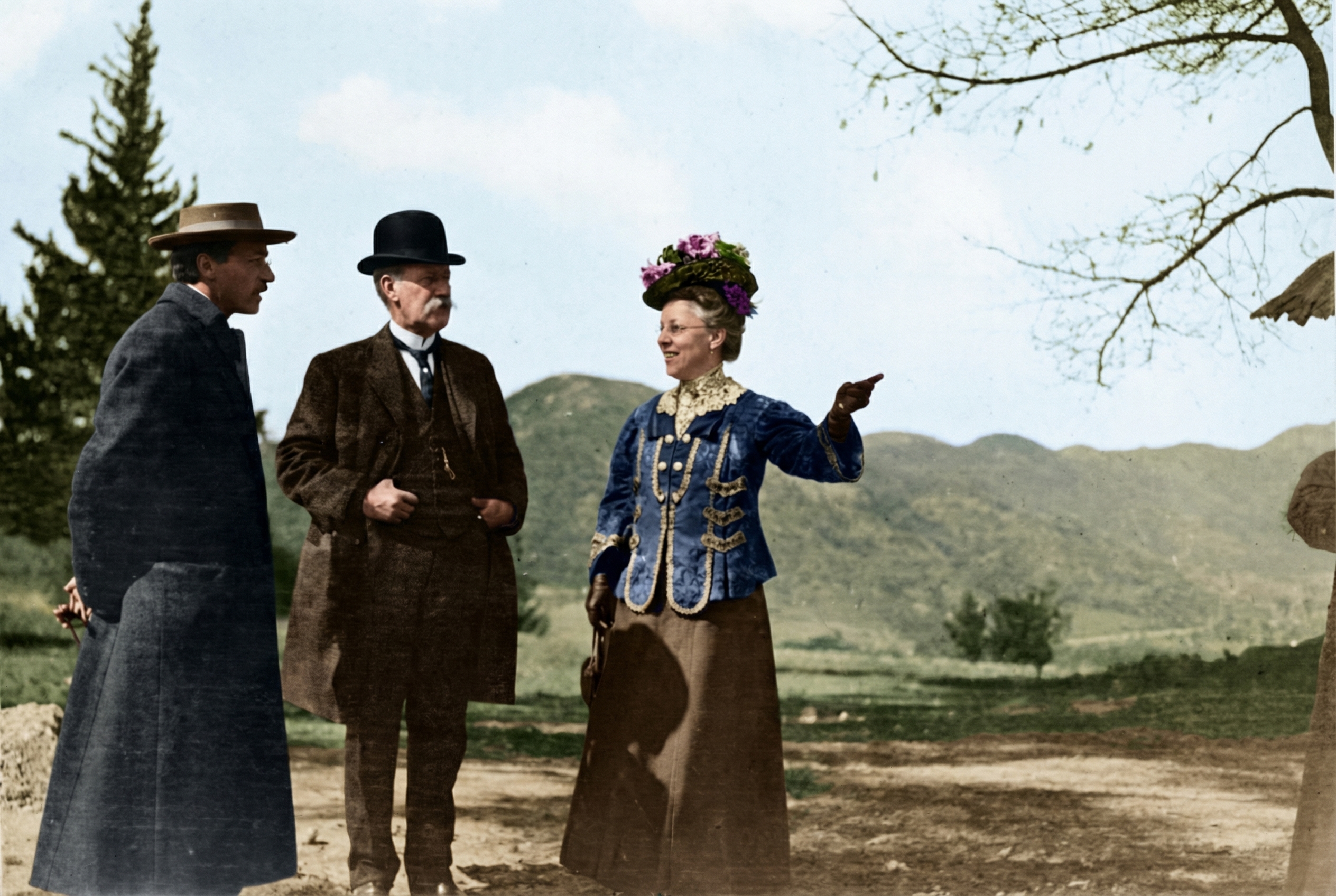 Historic sepia-toned photograph from circa 1908-1910 showing architect Charles Sumner Greene (center) standing with David B. Gamble (left) and Mary Gamble (right) on the grounds of the newly completed Gamble House.