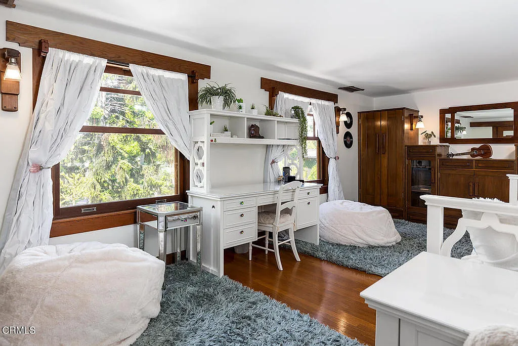 Third bedroom in the Laurabelle A. Robinson House with vaulted ceiling, wood paneling, built-in shelving, and large windows
