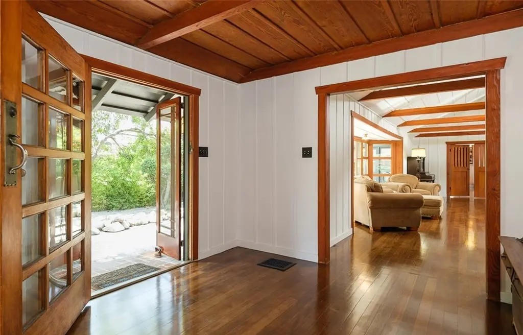Entrance hall with exposed beam ceiling, hardwood floors, and Arts and Crafts woodwork at Edgar W. Camp house