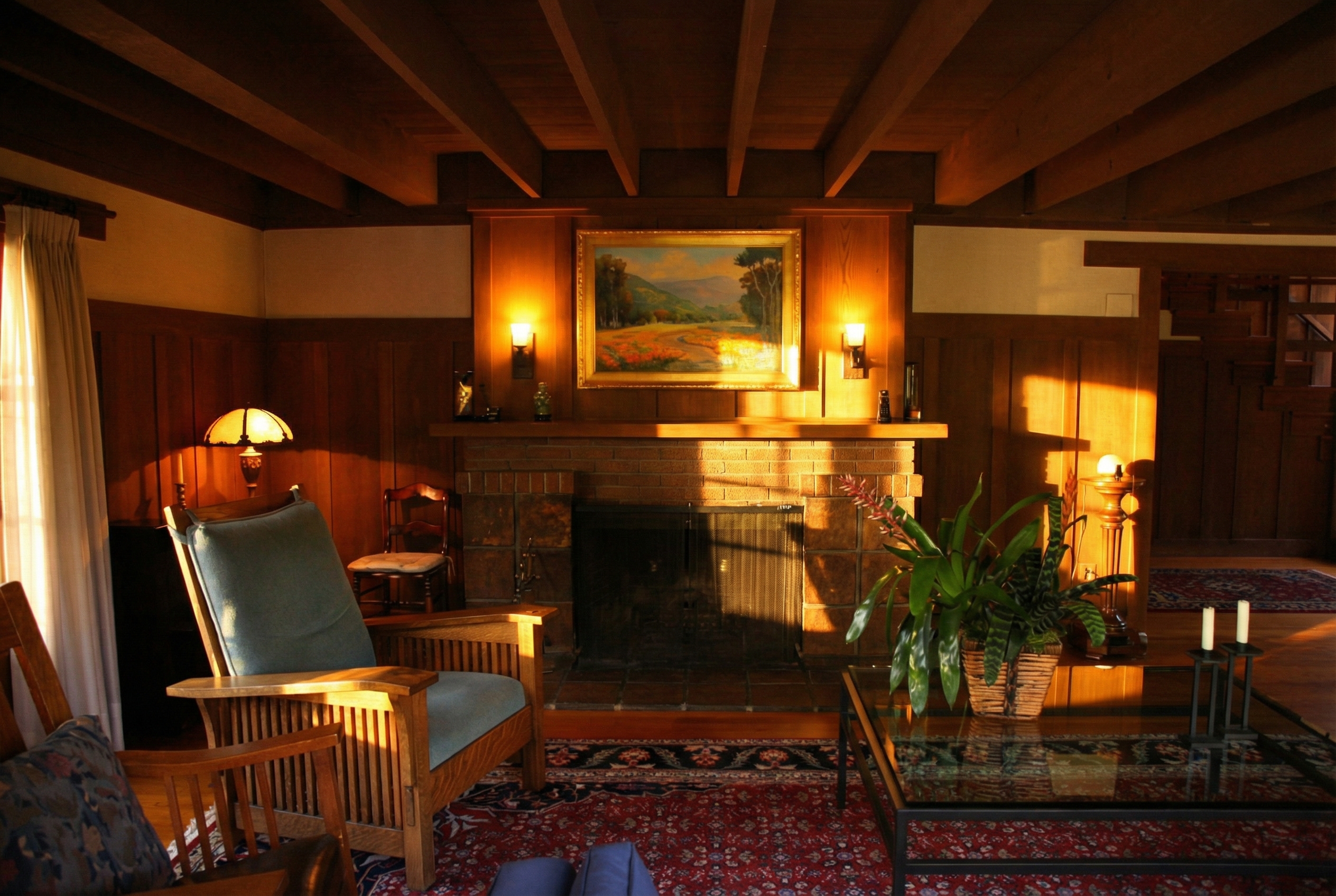 Living room interior showing exposed ceiling beams, brick fireplace with custom mantel in the van Rossem-Neil House.