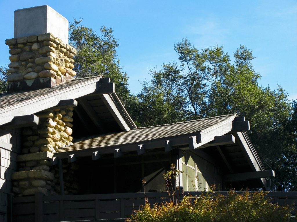 Exterior eaves and chimney detail of The Charles M. Pratt House showing Craftsman architecture and wood shingle roofing