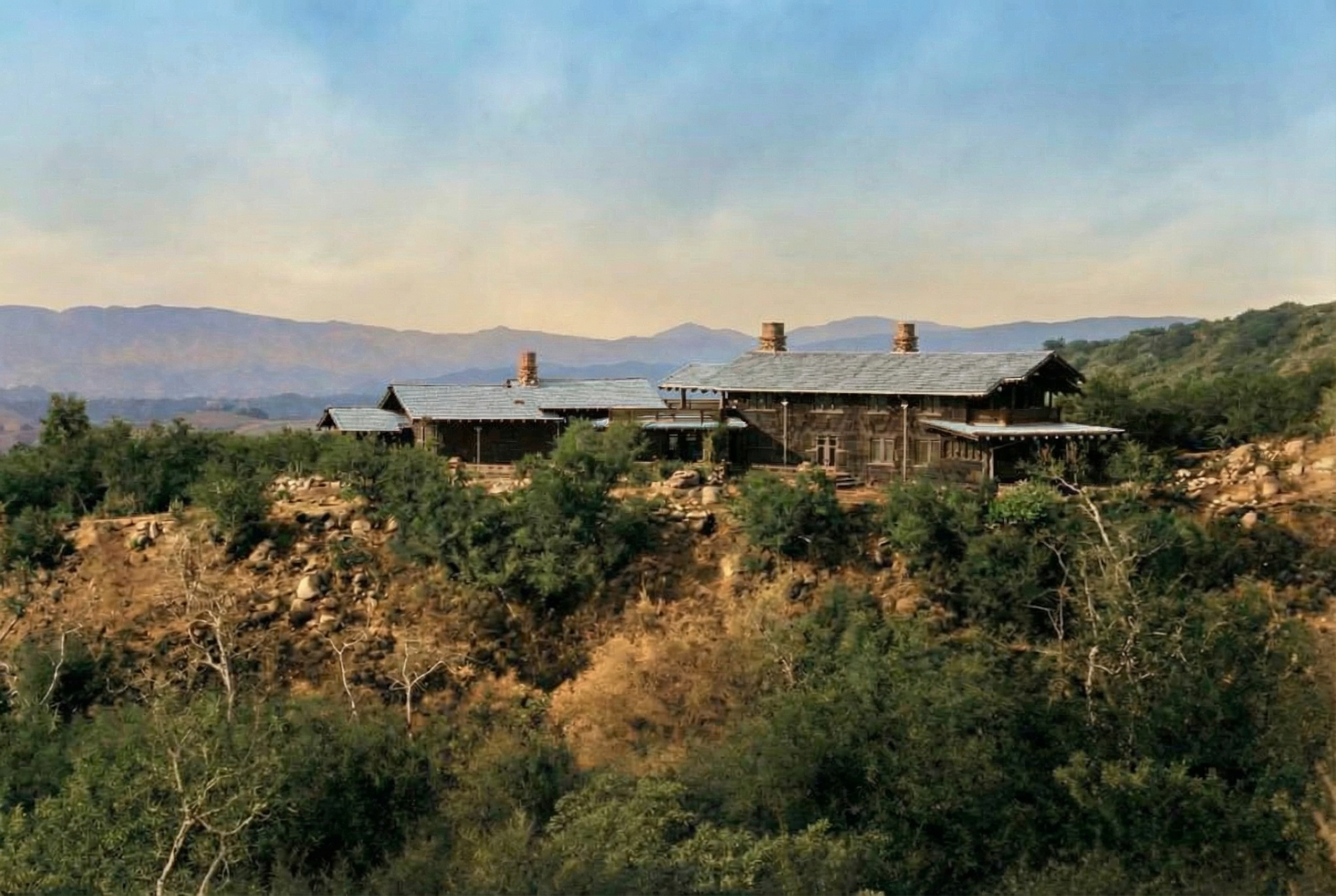 Historic colorized distant view of The Charles M. Pratt House showing full property, landscaping, and surrounding gardens