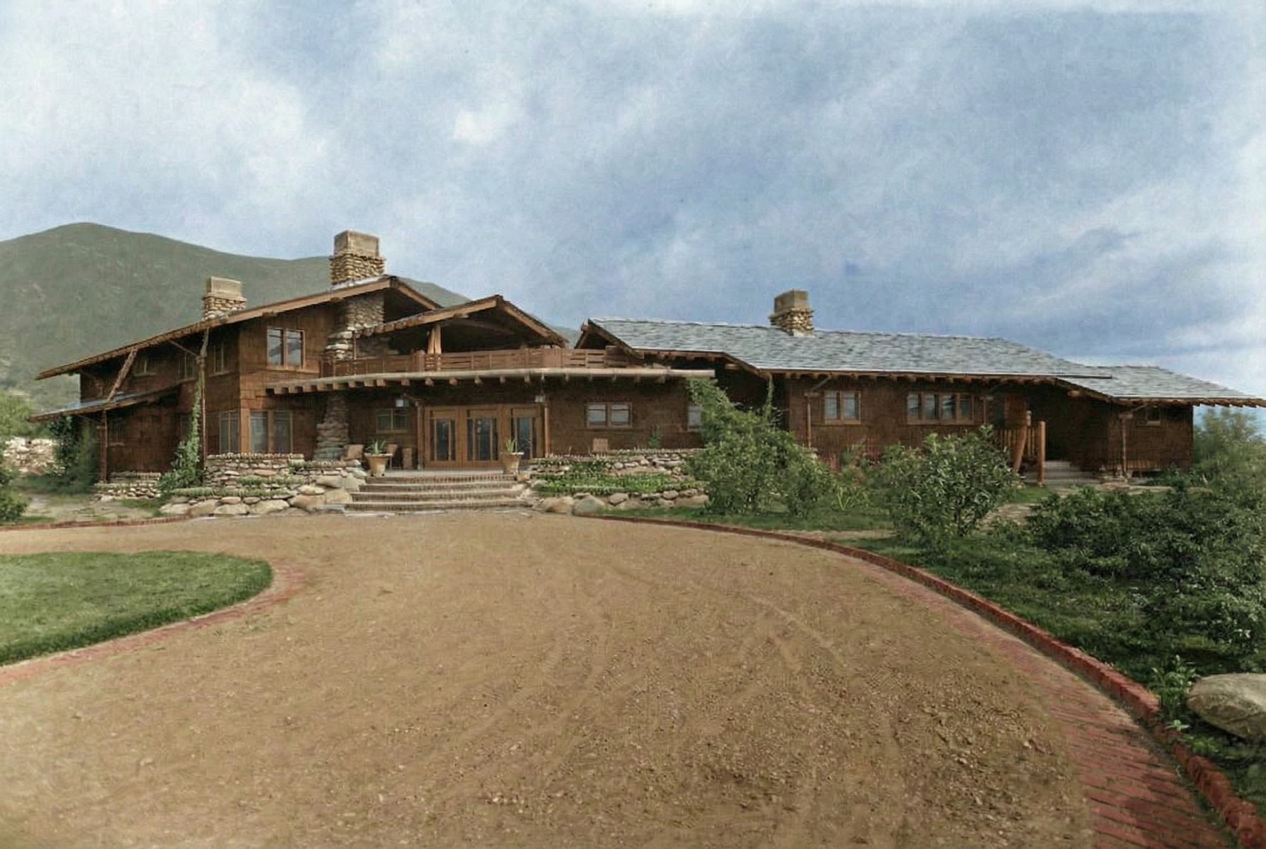Historic main photograph of The Charles M. Pratt House showing original landscaping, stone walls, and Craftsman architecture