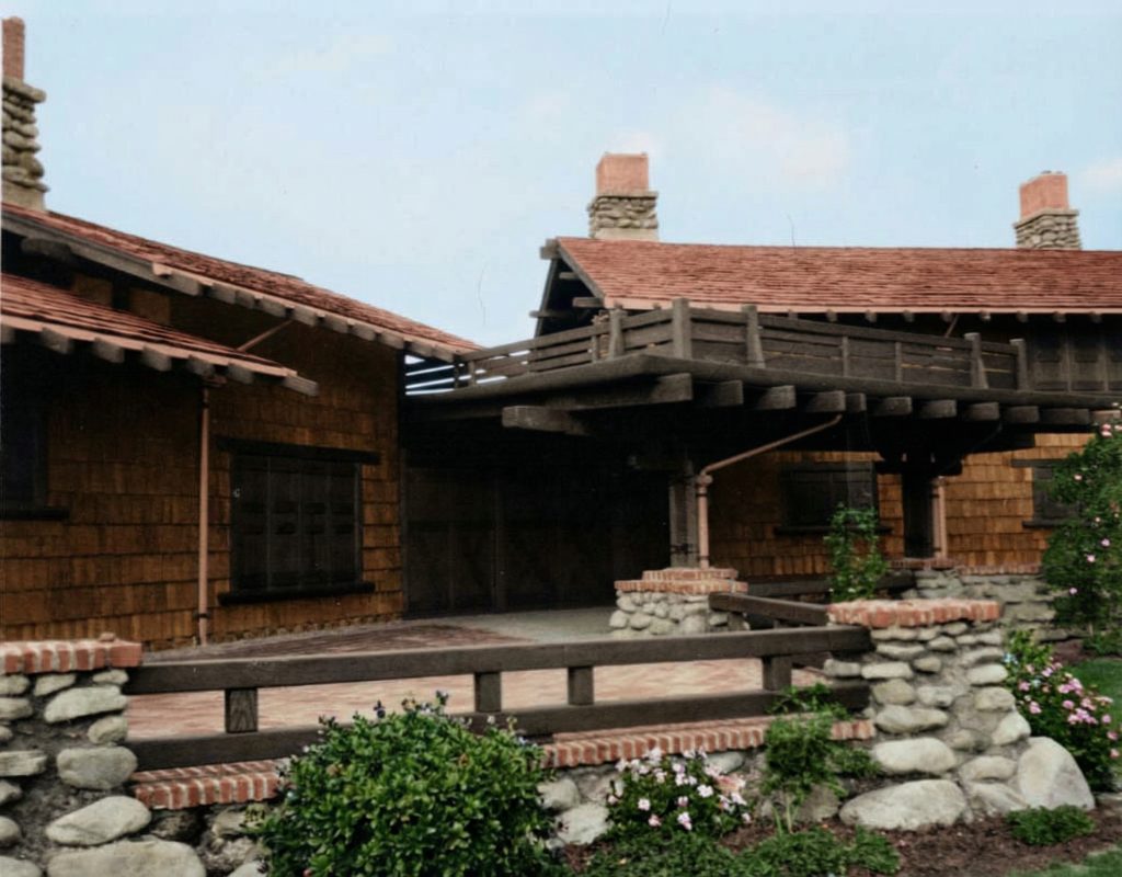 Historic photo of rear terrace showing exposed timber framing, river rock columns, and built-in benches overlooking the Ojai Valley.