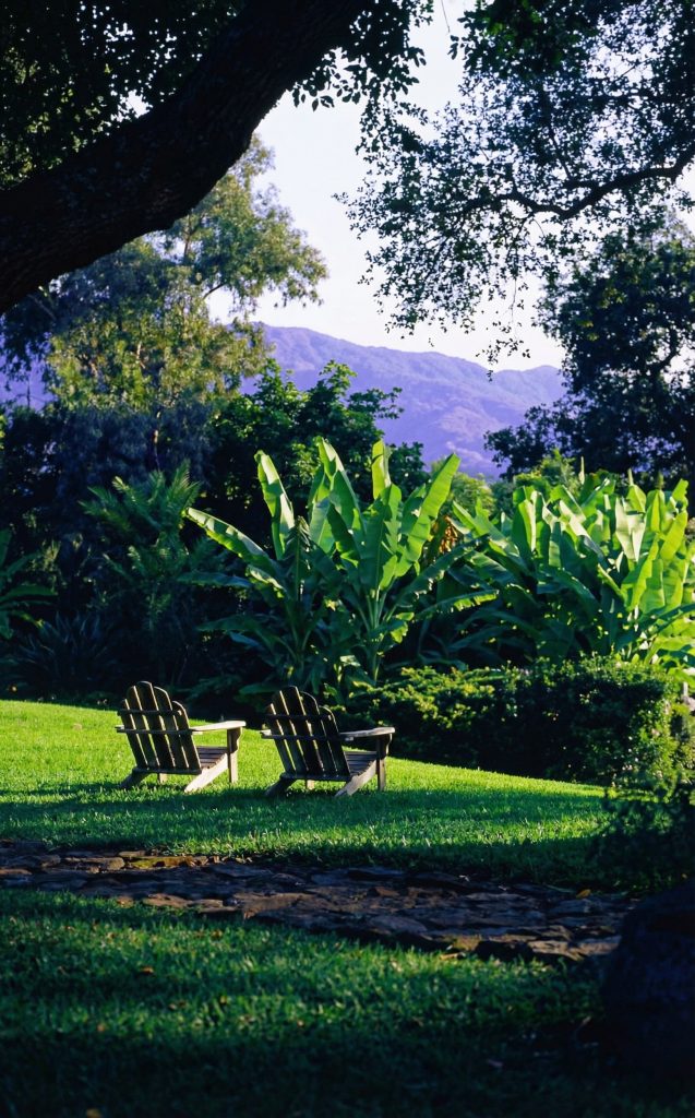 Landscaping view of The Charles M. Pratt House with lush gardens, stone pathways, mature trees, and terraced plantings