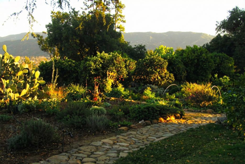 Landscaping view of The Charles M. Pratt House with terraced gardens, stone walls, pathways, and mature tree canopy