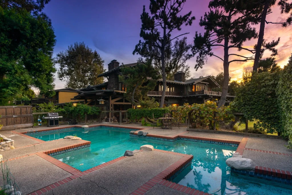 The Duncan-Irwin House irregular-shaped swimming pool surrounded by lush landscaping and stone walls.