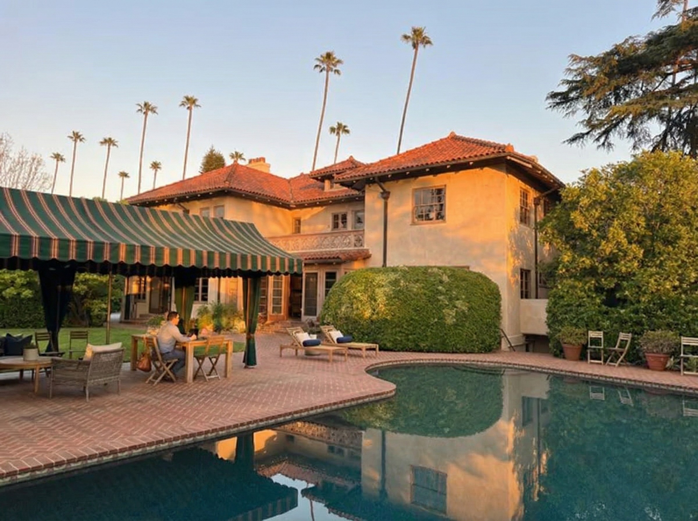 The rear of the Stimson House from across a rectangular reflecting pool, showing the back facade with arched openings, a covered terrace, and the surrounding garden.