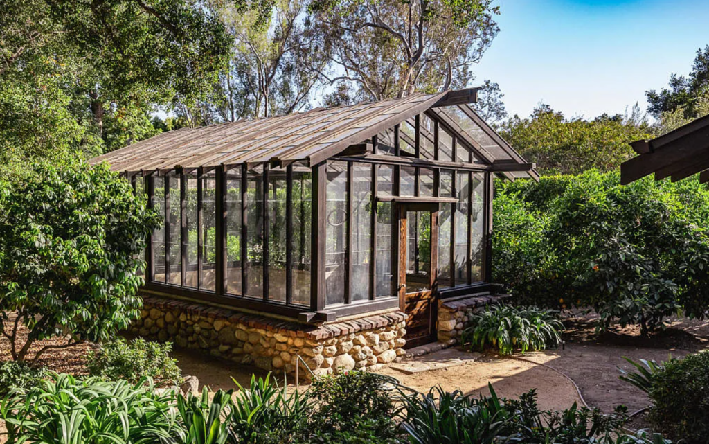 Greenhouse at the Louise C. Bentz House with glass panels, wood frame construction, and surrounding garden landscaping