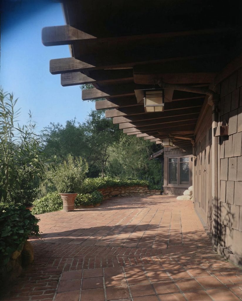 Colorized front terrace of The Charles M. Pratt House with stone paving, columns, pergola, and Arts and Crafts details