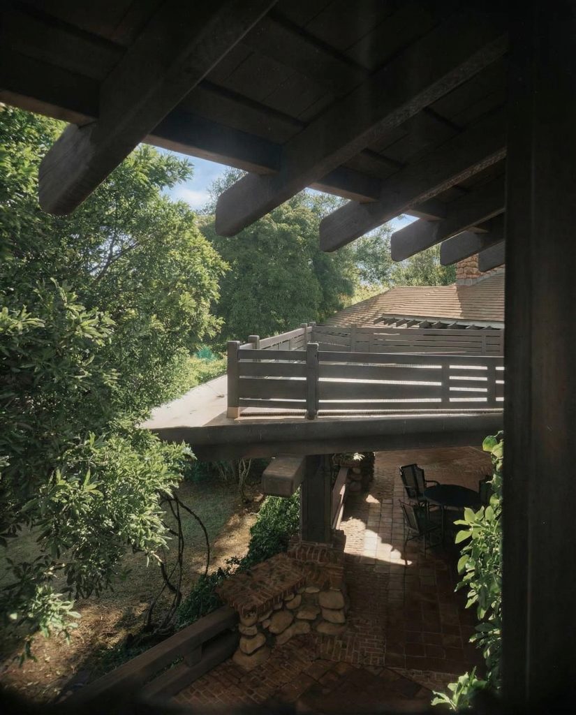 Colorized second floor view of terrace at The Charles M. Pratt House showing stone paving, columns, and gardens below