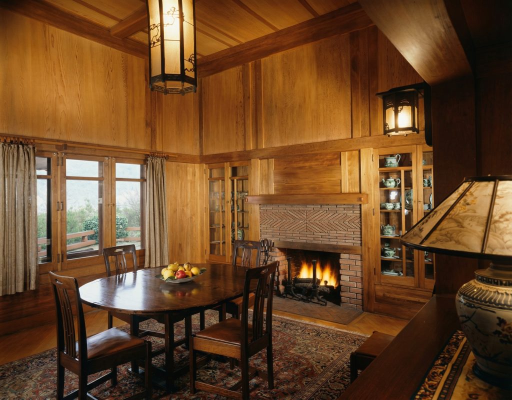 Colorized dining room of The Charles M. Pratt House with wood paneling, built-ins, chandelier, and Arts and Crafts details