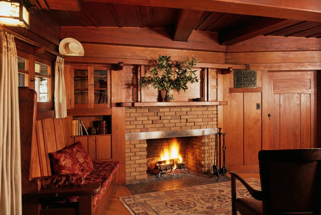 Colorized living room of The Charles M. Pratt House with fireplace, exposed beams, wood paneling, and period furnishings
