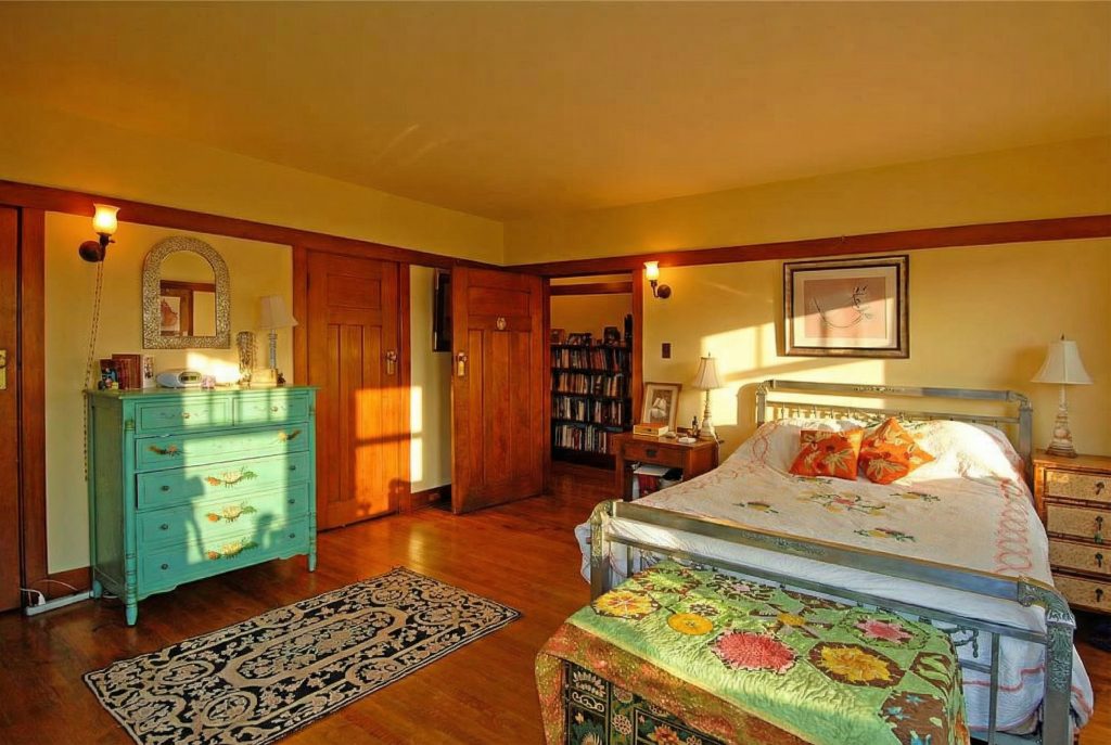 A bedroom in The Caroline S. de Forest House, with wood-paneled walls, a built-in dresser, and a serene, restful atmosphere.