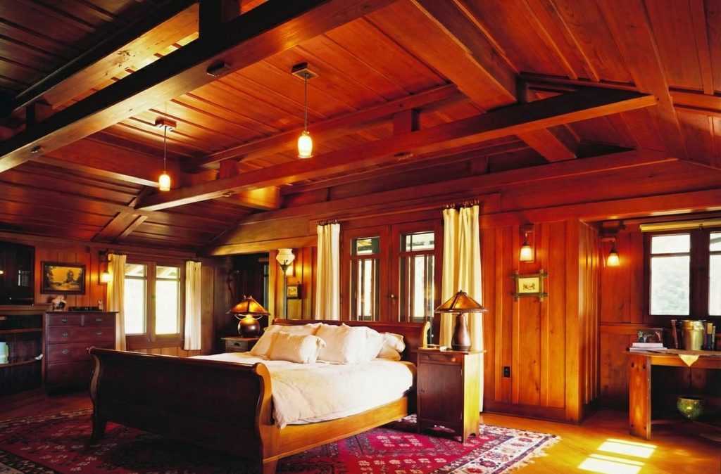 First bedroom of The Charles M. Pratt House with hardwood floors, built-ins, fireplace, windows, and period furnishings