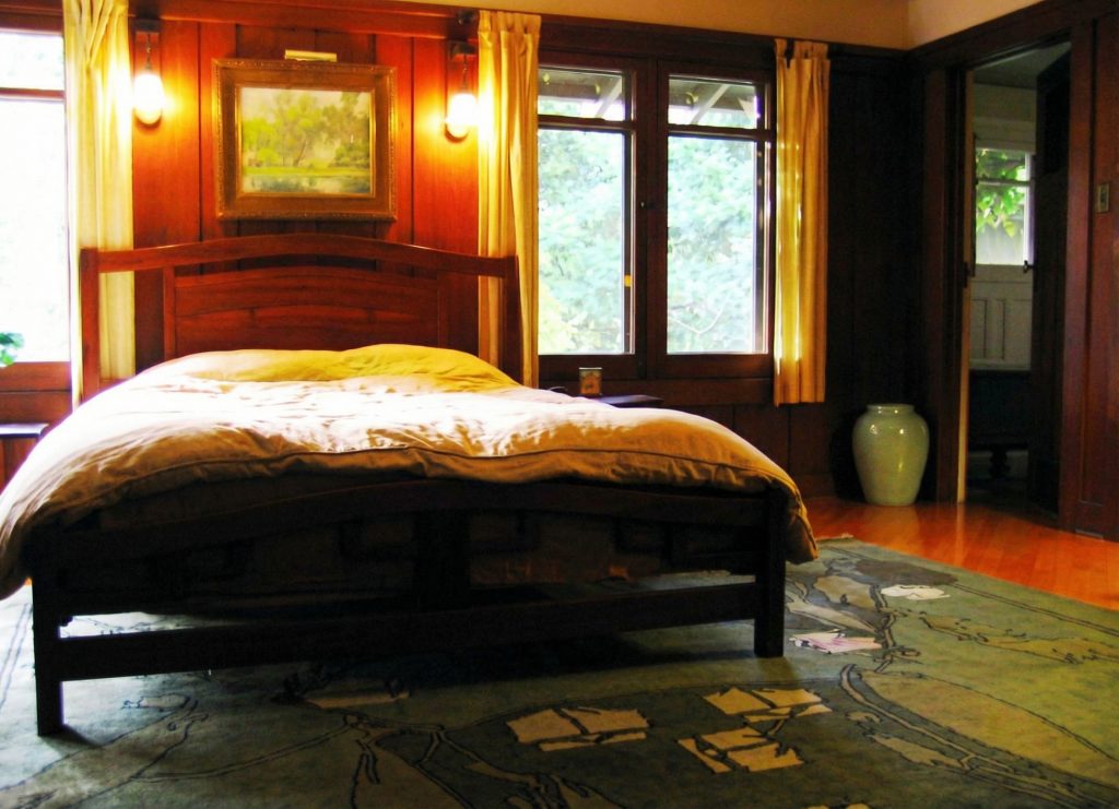 Second bedroom of The Charles M. Pratt House with hardwood floors, fireplace, built-in cabinetry, and large windows