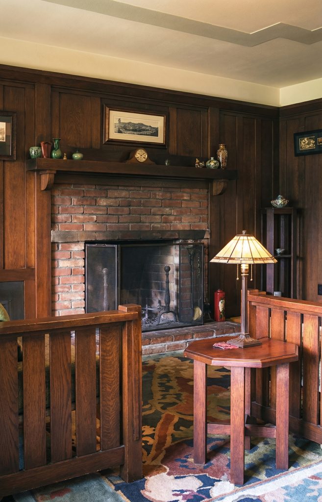 Third bedroom sitting area fireplace at The Charles M. Pratt House with decorative tile, wood mantel, and built-ins