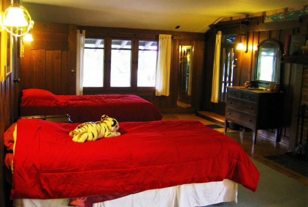 Fourth bedroom of The Charles M. Pratt House with hardwood floors, fireplace, built-in cabinetry, and large windows