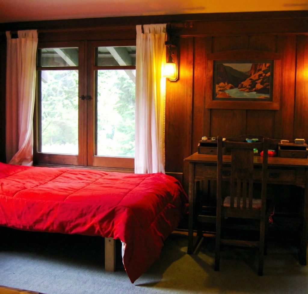 Fourth bedroom window at The Charles M. Pratt House with wood casement frames, built-in seating, and garden views