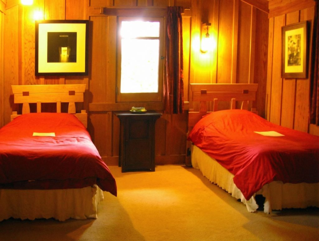 First servants' bedroom at The Charles M. Pratt House with simple wood floors, built-in storage, and functional design