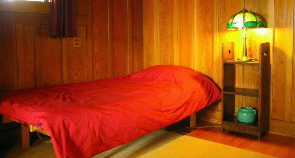 Second servants' bedroom at The Charles M. Pratt House with hardwood floors, built-in cabinetry, and simple furnishings