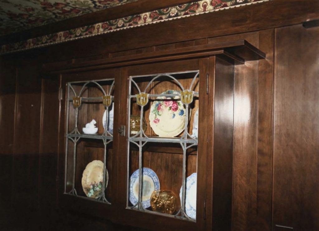 Built-in cabinet at The Jennie A. Reeve House with leaded glass shelves displaying decorative china and Arts and Crafts details