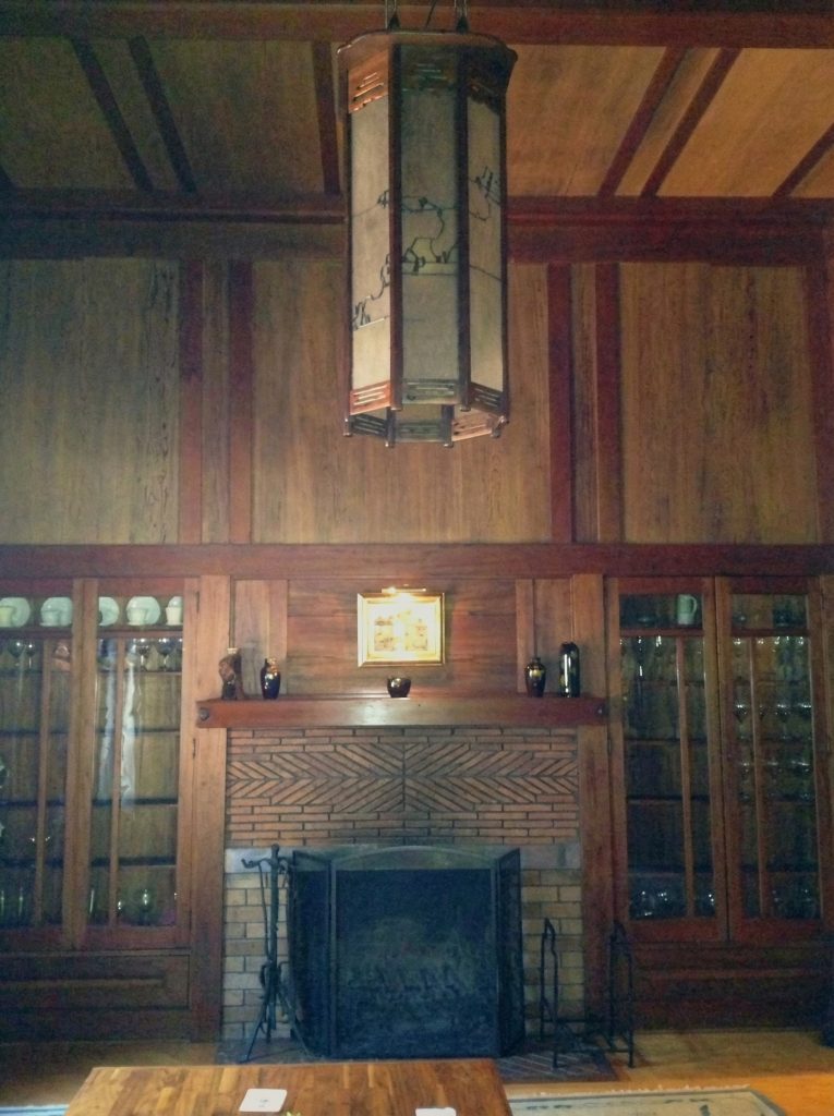 Dining room of The Charles M. Pratt House with wood paneling, built-in sideboard, chandelier, and Arts and Crafts details


