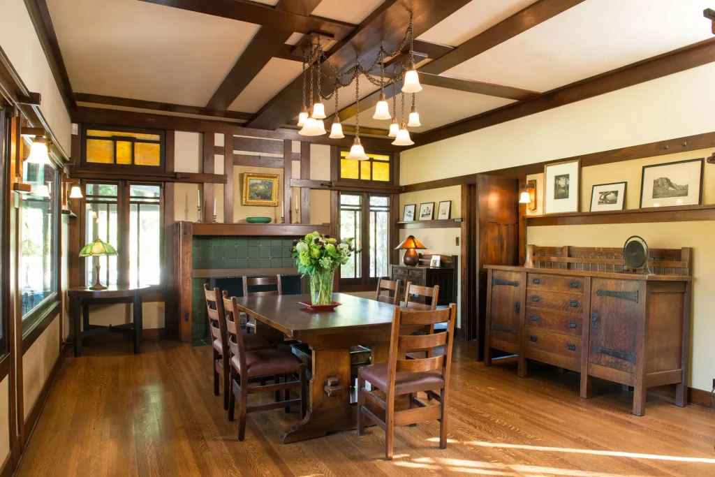The Duncan-Irwin House dining room with period furnishings, tile fireplace, and multi-bulb light fixture.