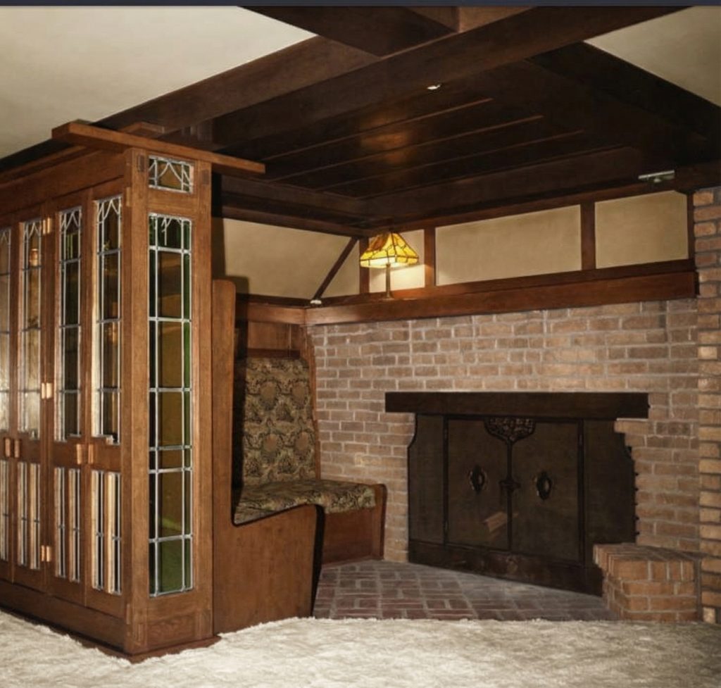 Inglenook at The Jennie A. Reeve House with brick fireplace, leaded glass room divider, exposed beams, and built-in seating