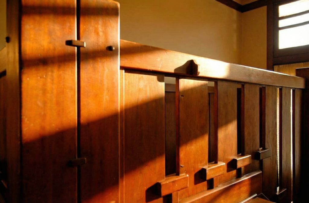A detail of the staircase handrail in The Caroline S. de Forest House, showcasing the smooth, softened edges of the woodwork.