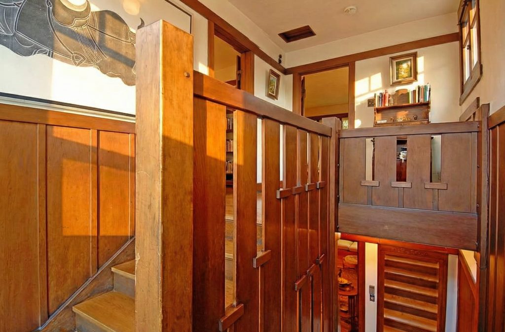 The upstairs landing of the staircase in The Caroline S. de Forest House, with its warm wood paneling and serene atmosphere.