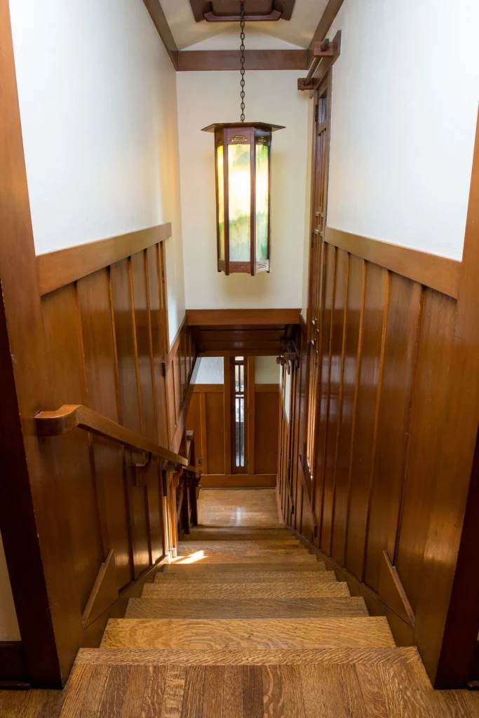 Stairwell of The Duncan-Irwin House featuring craftsman details and wisteria-themed art glass.