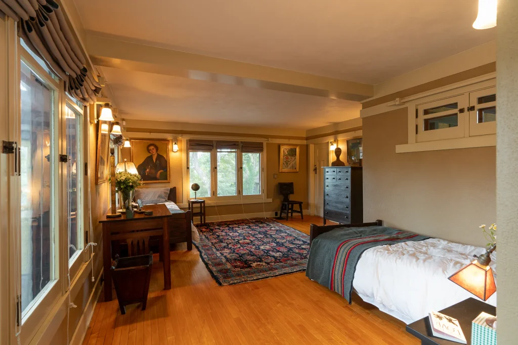 Second-floor bedroom No. 2 of The Duncan-Irwin House with fireplace and wrap-around windows.