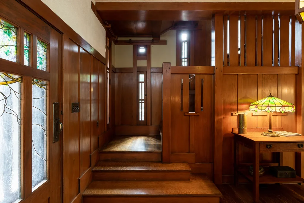 Main stairway of The Duncan-Irwin House with wood paneling and stained-glass light fixture above.