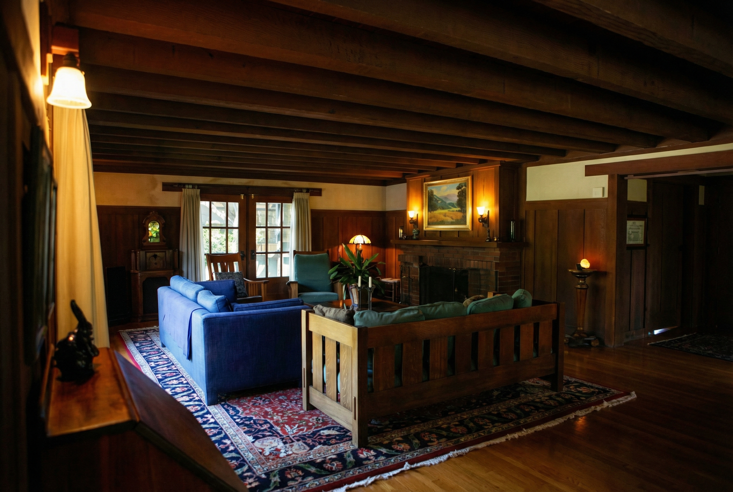 Main living room view featuring variable-width ceiling beams, natural wood finishes, built-in furniture, and Arts and Crafts design elements in the van Rossem-Neil House.