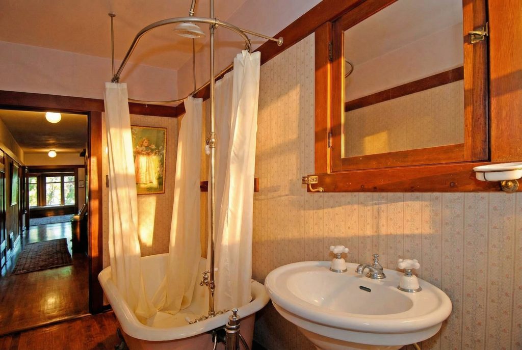 A vintage-style bathroom in The Caroline S. de Forest House, with a clawfoot tub, pedestal sink, and warm, natural light.