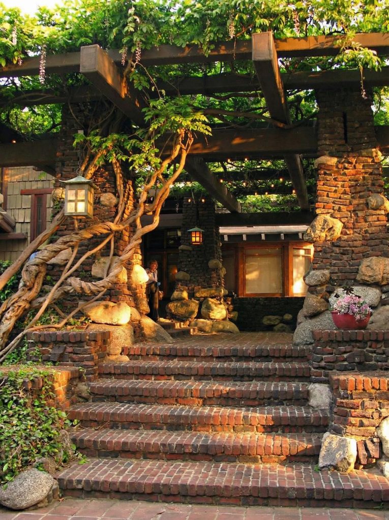 The Duncan-Irwin House iconic pergola with Arroyo stone columns and wisteria vines at formal entrance.