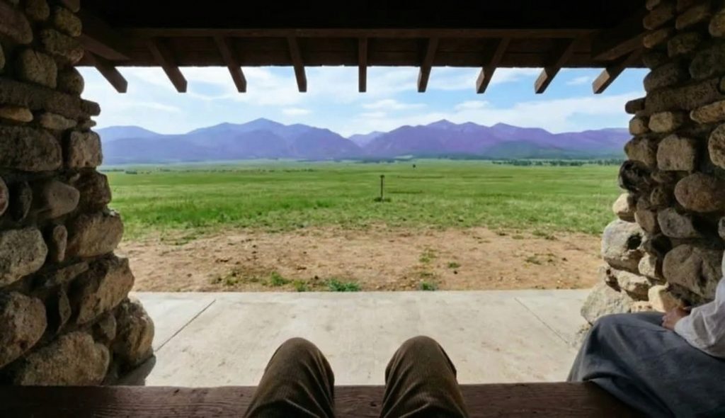 Interior view from seated position inside a Greene & Greene stone pavilion looking out at mountain landscape