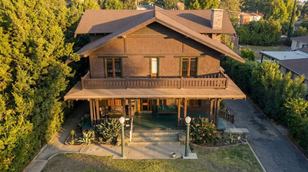 Aerial front elevation of The Ernest W. Smith House highlighting its broad gable, balcony, and full-width porch