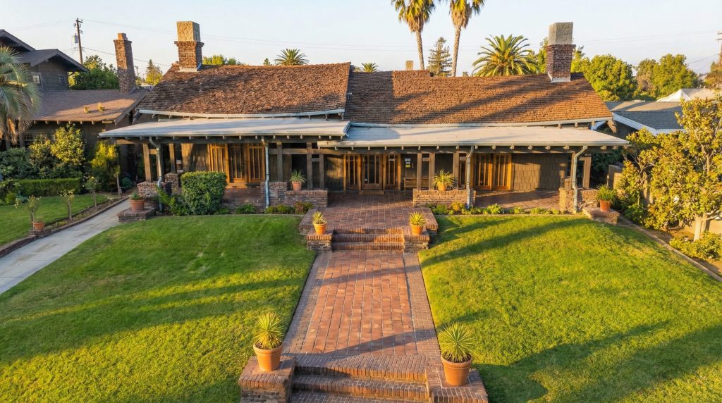 An aerial view of The Dr. S. S. Crow House, showing the U-shaped plan, the central courtyard, surrounding lush gardens, and the large pool.
