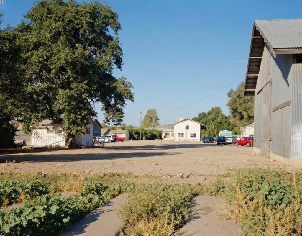 Distant exterior photograph of the east elevation of The Sespe Ranch Bunkhouse framed by surrounding ranch grounds and trees