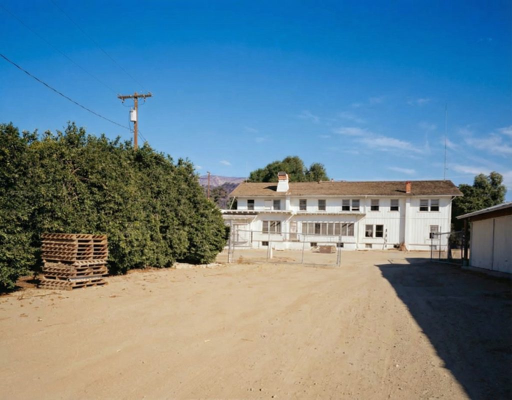 Distant exterior view of the south elevation of The Sespe Ranch Bunkhouse with the surrounding Rancho Sespe agricultural landscape