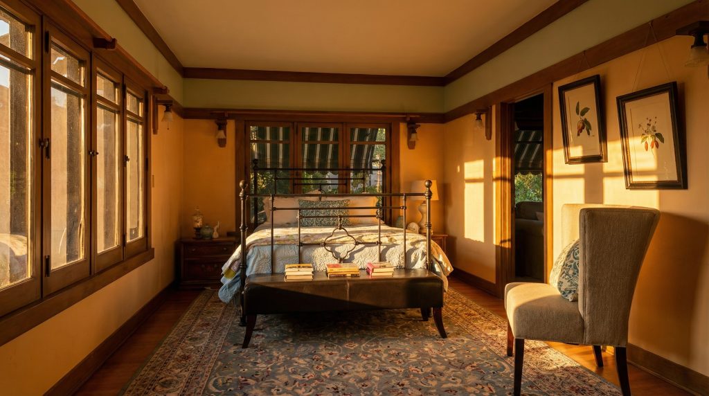 A serene bedroom in The Dr. S. S. Crow House, featuring simple, elegant furnishings, abundant natural light, and beautifully finished wood trim.