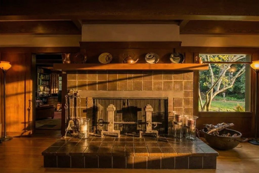 Craftsman fireplace with a raised tile hearth and rich wood paneling inside The Earle C. Anthony house living room