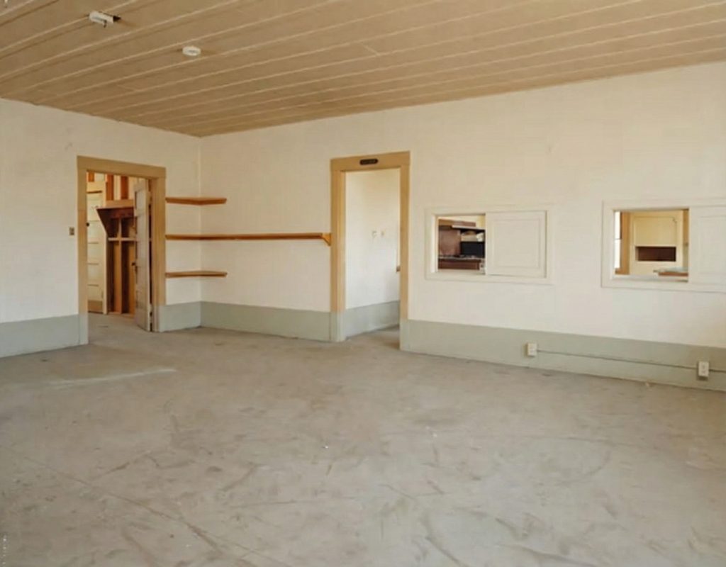 Interior view of the first floor dining room of The Sespe Ranch Bunkhouse showing beadboard ceiling, doorways, and service windows
