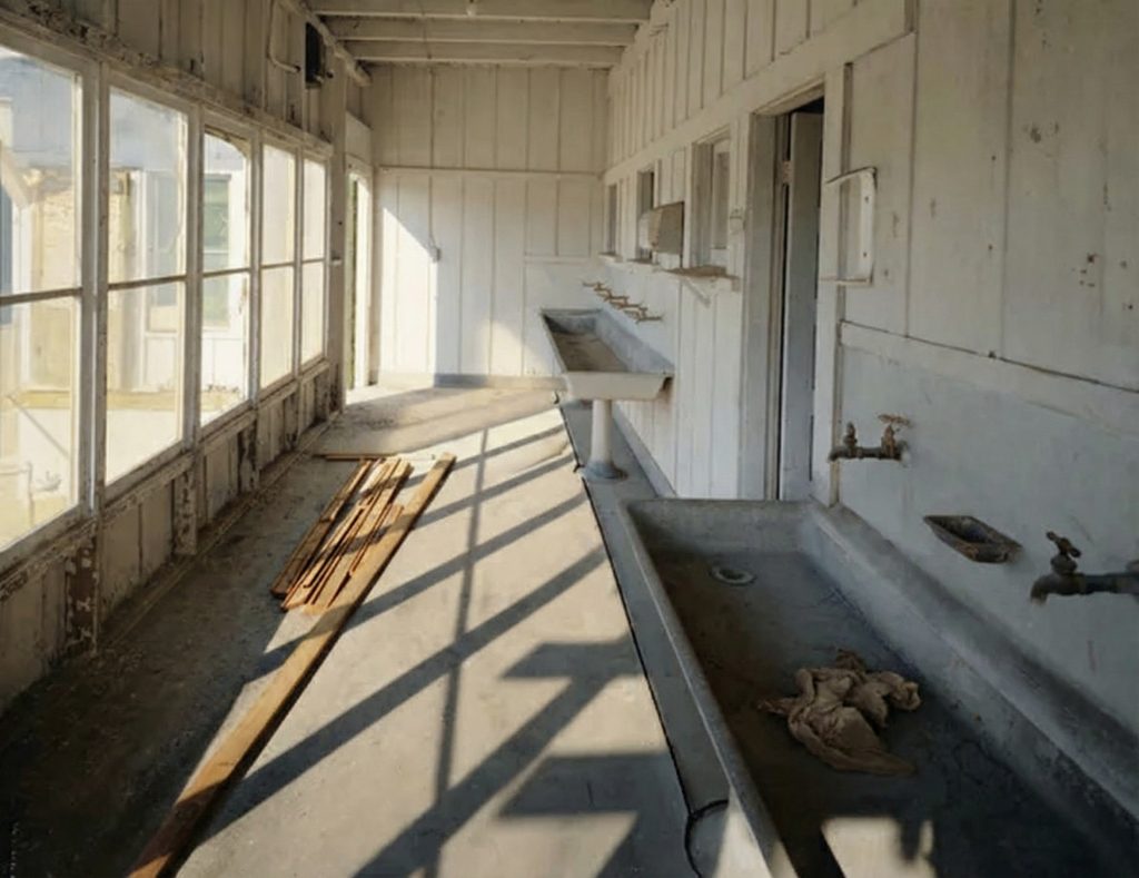 Interior of the first floor wash room of The Sespe Ranch Bunkhouse with long concrete trough sink, faucets, and sunlit windows