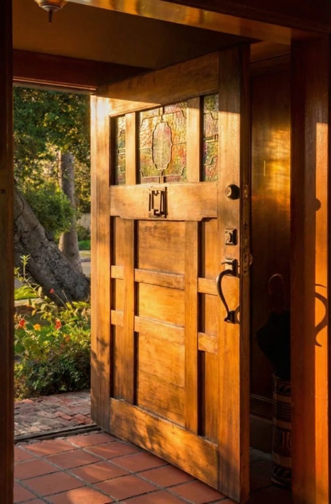Interior view of the front door entry at The Earle C. Anthony house featuring wood paneling and art glass sidelights
