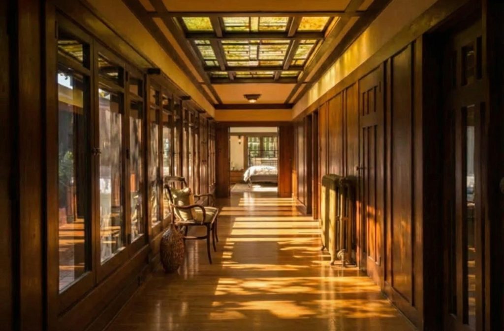 The bright, airy sunroom of The Dr. S. S. Crow House, illuminated by a large skylight and surrounded by windows that connect it to the garden.
