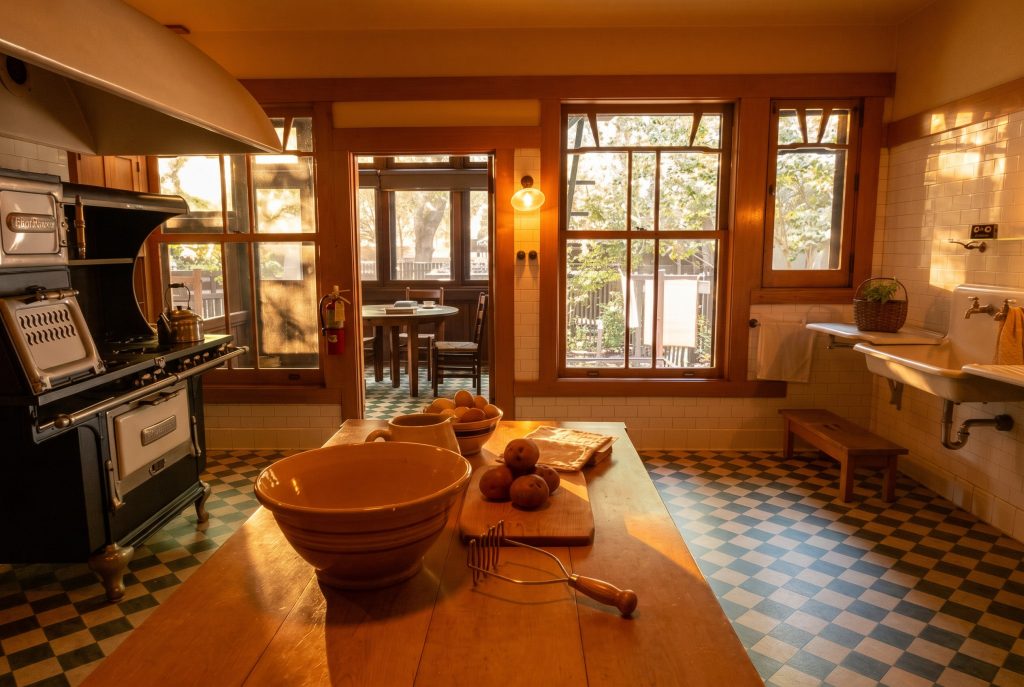 Another view of the Gamble House kitchen, showing light pale woodwork, generous windows, and a practical, well-organized working plan